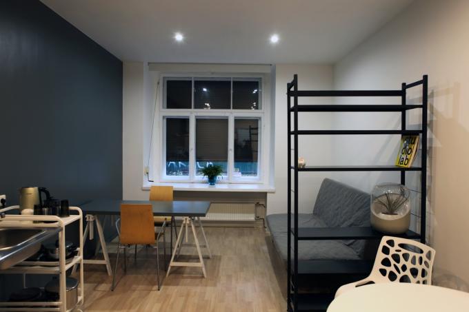 Residency Apartment Riga, a room with a chouch, a shelf, and some tables