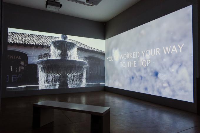 Gallery Space with a bench and a projection on the wall