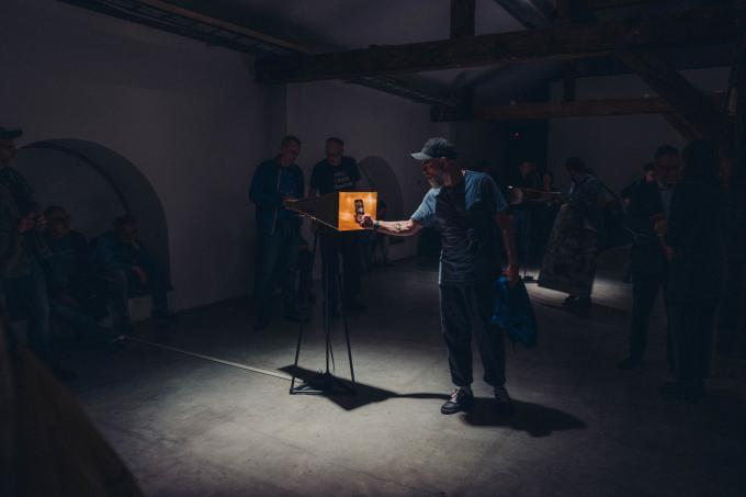 A person taking a picture of an art piece in a dark room